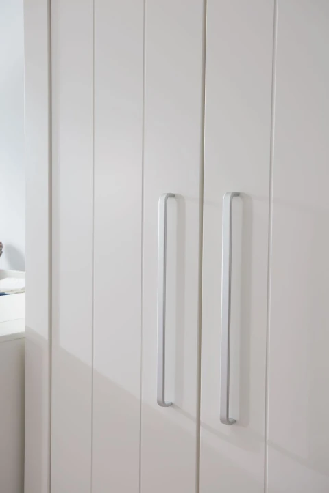 Aluminiowe uchwyty w białej szafie Calmo