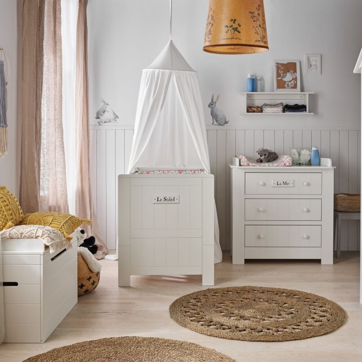 Komoda z szufladami i przewijakiem Marsylia ustawiona obok łóżeczka z tej samej kolekcji. Aranżacja pokoju niemowlaka.