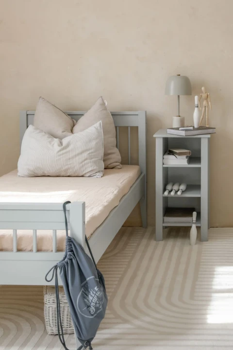 Regał niski Collet w pastelowym kolorze przy łóżku dziecięcym