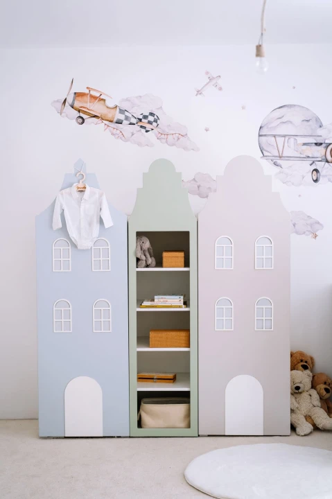 Regał domek na książki i zabawki do pokoju dziecka ustawiony między szafami z kolekcji Kamieniczki